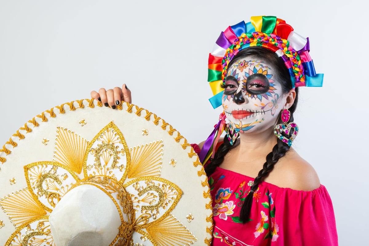 Mujer con maquillaje de Día de Muertos sosteniendo un sombrero de charro